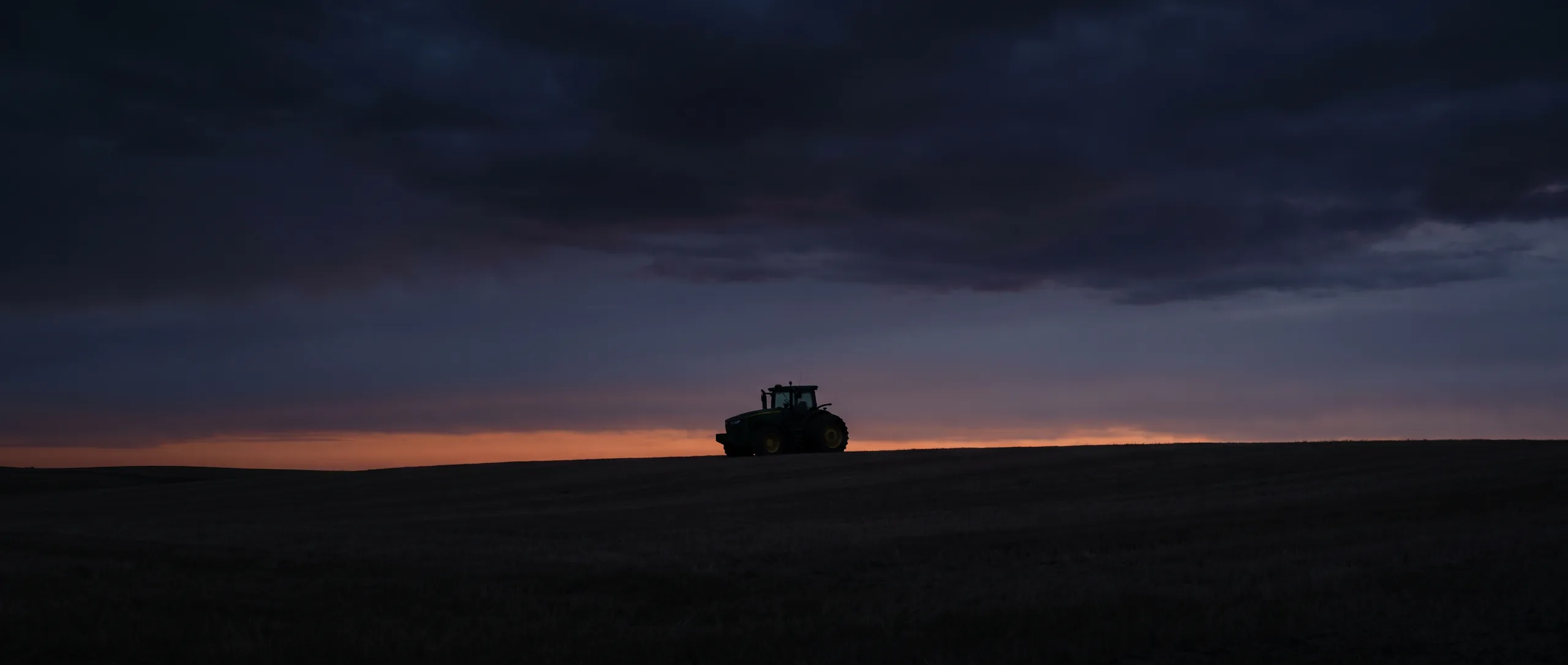 A worked field running out to the horizon at dusk